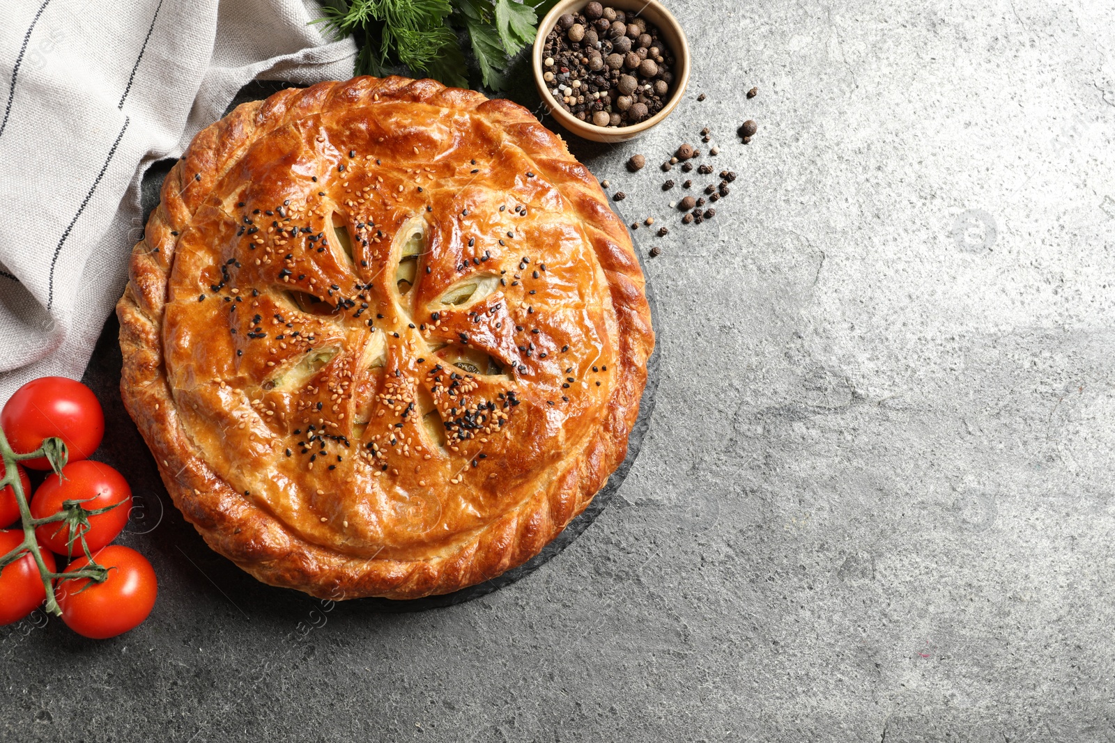 Photo of Tasty homemade pie, spices and fresh tomatoes on grey table, flat lay. Space for text