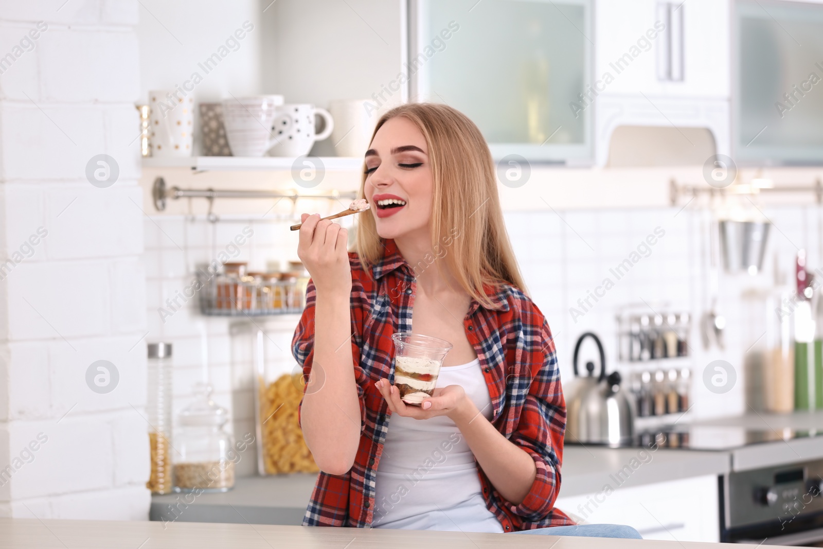 Photo of Young woman with yogurt in kitchen