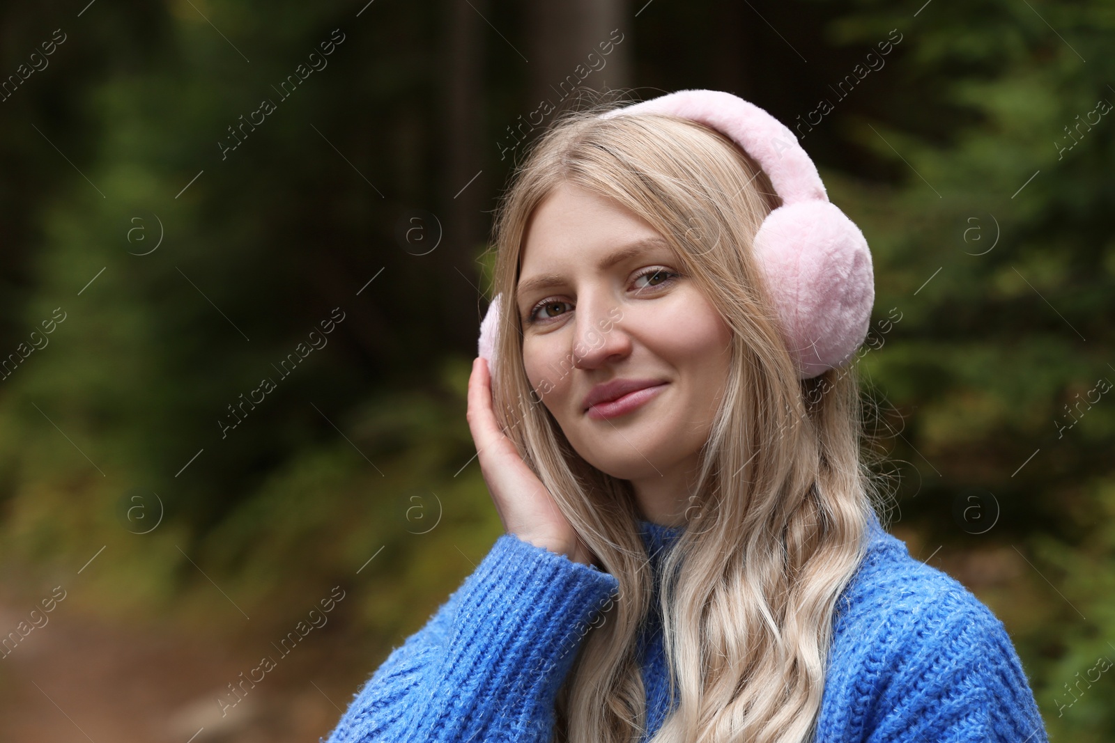 Photo of Young beautiful woman wearing warm earmuffs outdoors