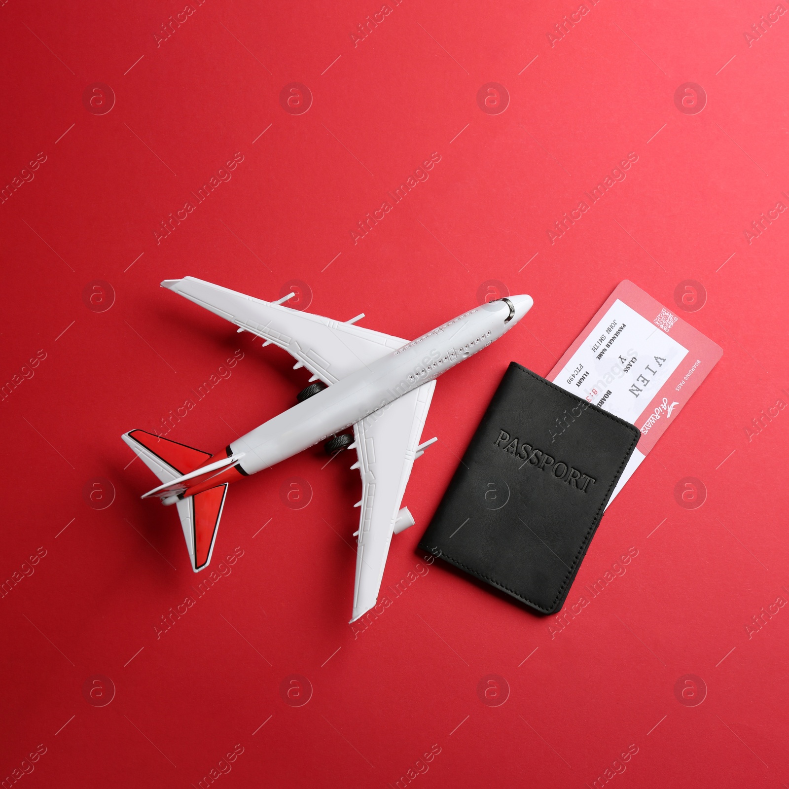 Photo of Toy airplane and passport with ticket on red background, flat lay