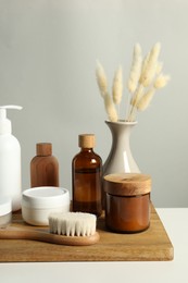 Photo of Different bath accessories and spikes on white table against grey background