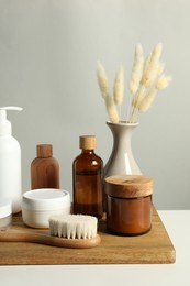 Different bath accessories and spikes on white table against grey background