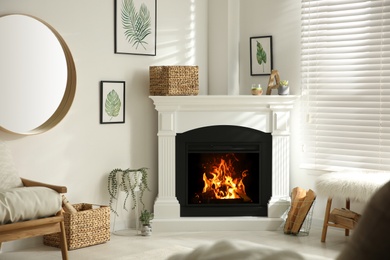 Photo of Bright living room interior with artificial fireplace and firewood in basket