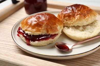 Freshly baked soda water scones with cranberry jam on wooden table, closeup