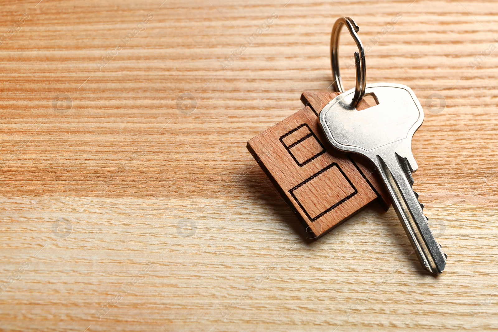 Photo of Key with trinket in shape of house on wooden background. Real estate agent services