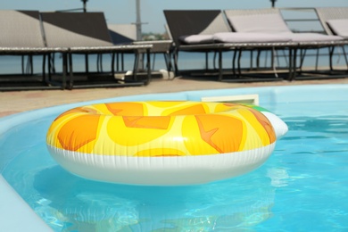 Colorful inflatable ring floating in swimming pool on sunny day, outdoors