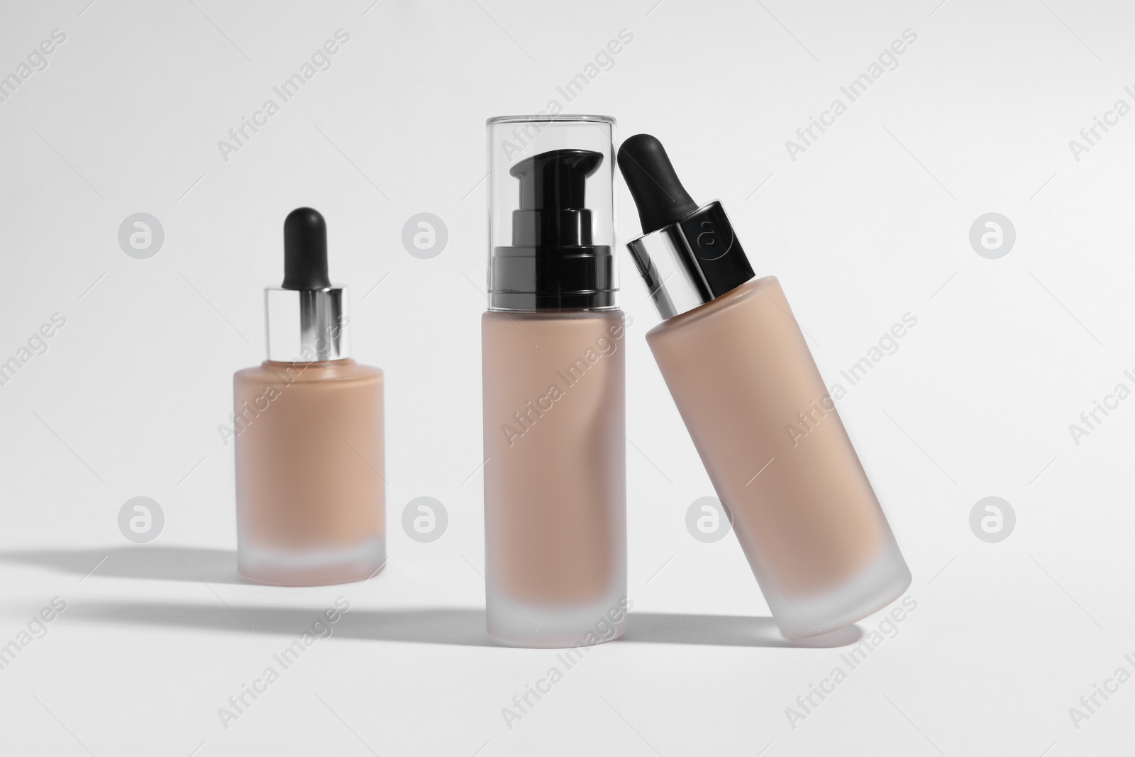 Photo of Bottles of skin foundation on white background. Makeup product