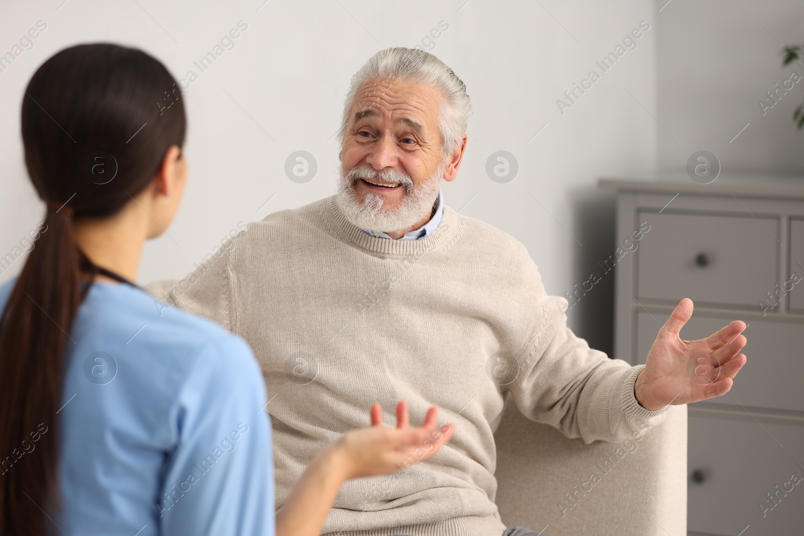 Photo of Smiling elderly patient laughing with nurse in hospital