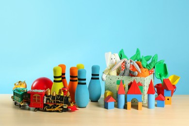 Photo of Many different toys on wooden table against light blue background