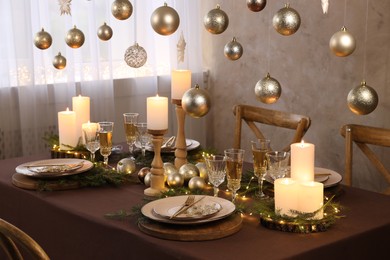 Photo of Christmas table setting with burning candles and festive decor