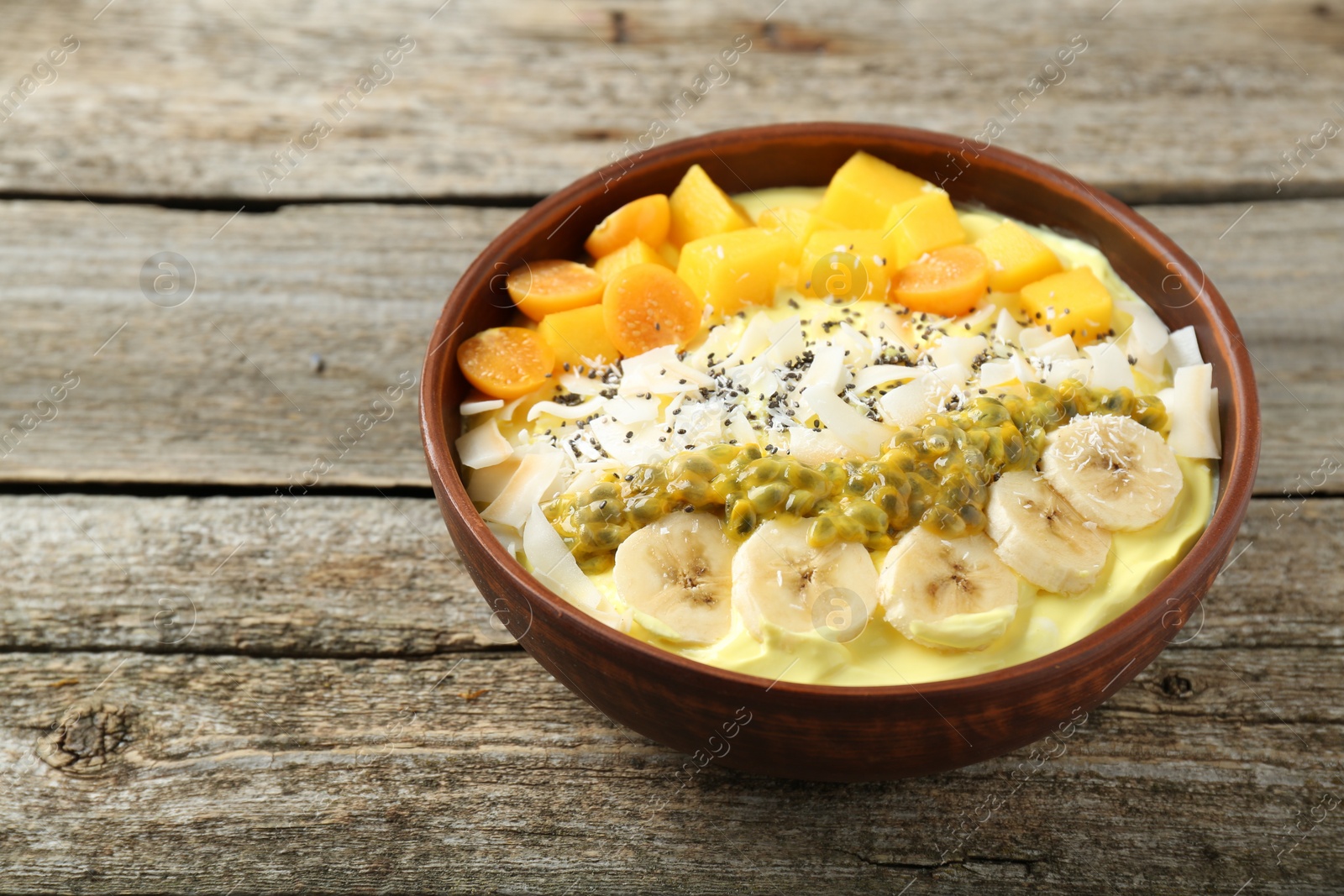 Photo of Tasty smoothie bowl with fresh fruits on wooden table, closeup. Space for text