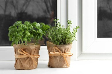 Photo of Aromatic potted basil and thyme on windowsill indoors. Space for text