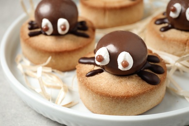 Photo of Delicious biscuits with chocolate spiders in tray, closeup. Halloween celebration