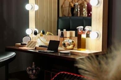 Photo of Makeup brushes and cosmetic products on dressing table in room