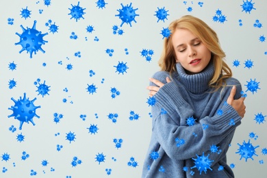 Stronger immunity - better disease resistance. Young woman wearing warm blue sweater surrounded by viruses on light background