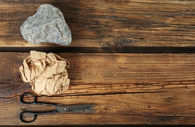 Photo of Flat lay composition with rock, paper and scissors on wooden background. Space for text