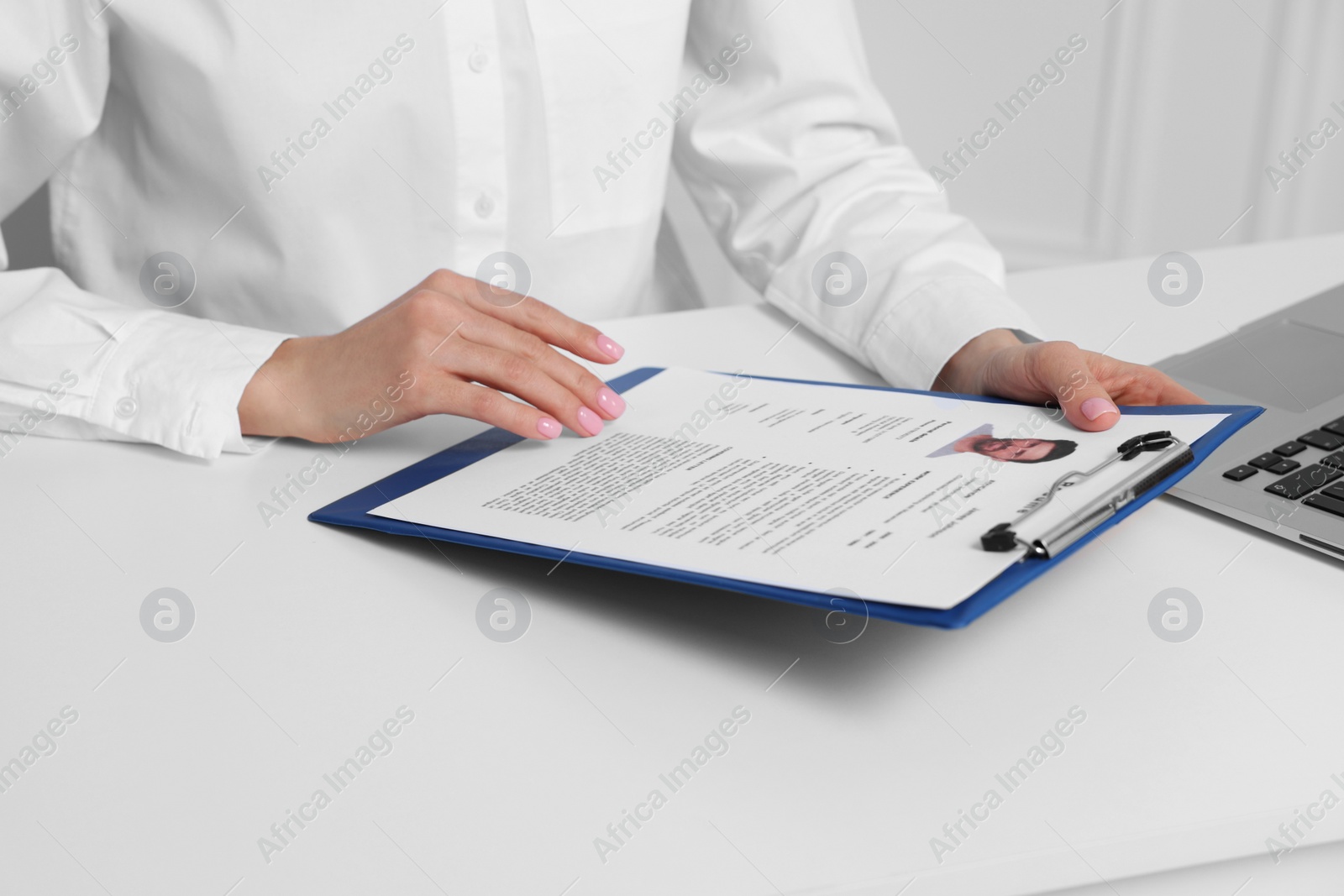 Photo of Human resources manager reading applicant's resume at white table, closeup