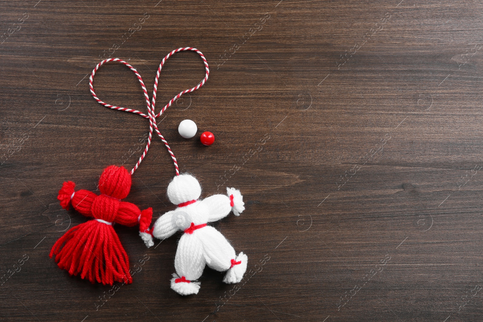 Photo of Traditional martisor shaped as man and woman on wooden background, flat lay with space for text. Beginning of spring celebration