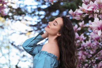 Beautiful woman near blossoming magnolia tree on spring day