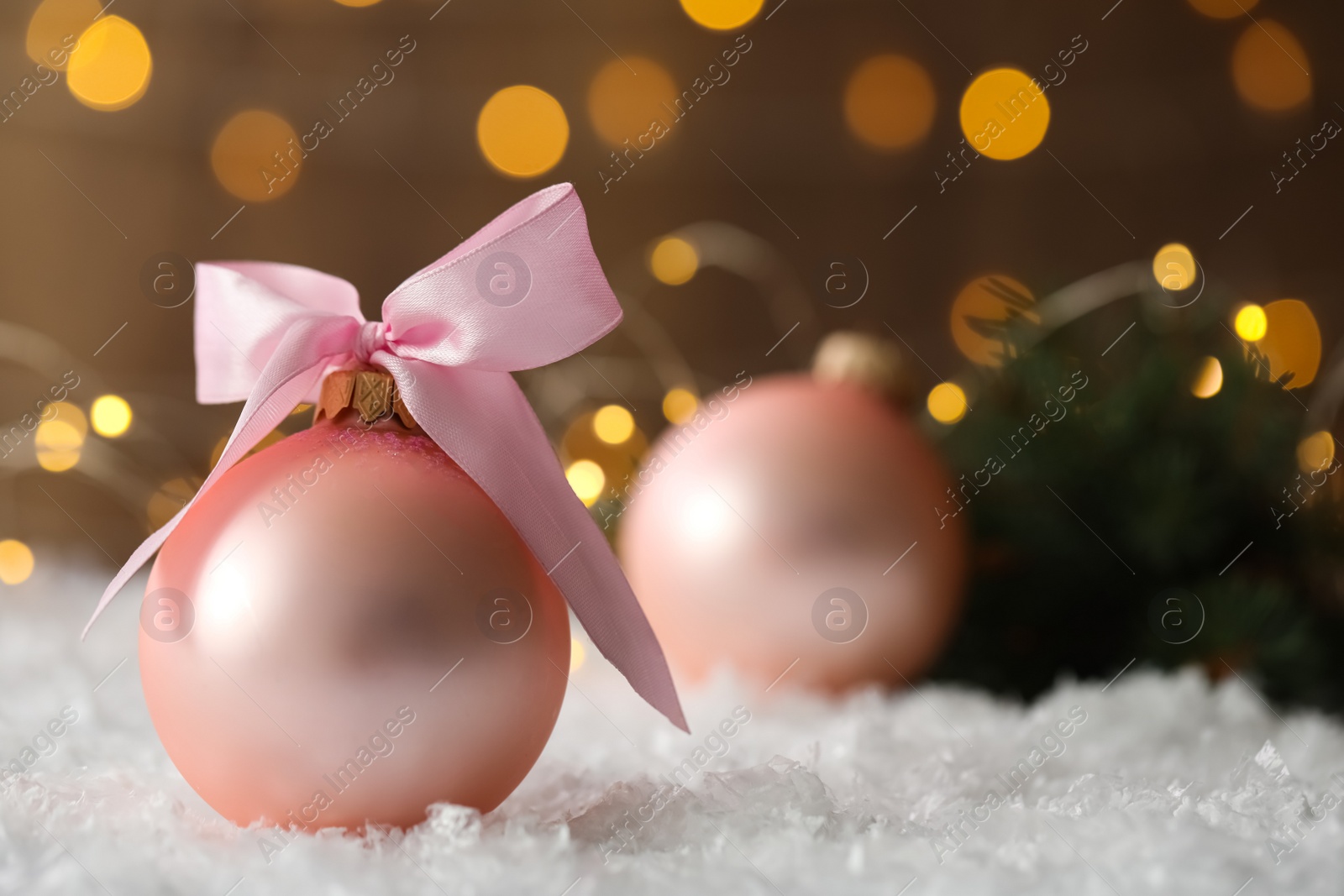 Photo of Beautiful Christmas ball on snow against blurred festive lights. Space for text