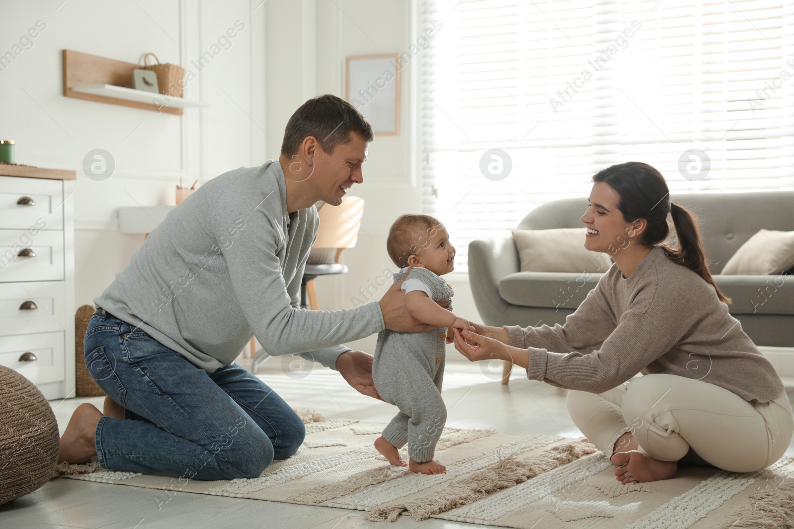 Photo of Parents supporting their baby daughter while she learning to walk at home