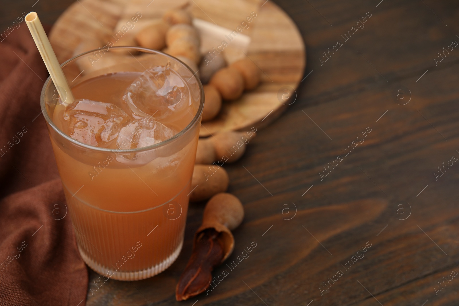 Photo of Freshly made tamarind juice and fresh fruits on wooden table, closeup. Space for text