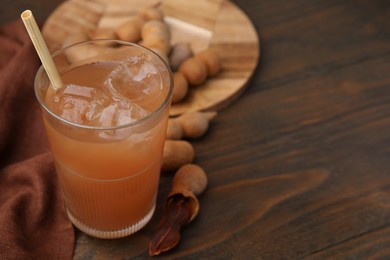 Photo of Freshly made tamarind juice and fresh fruits on wooden table, closeup. Space for text