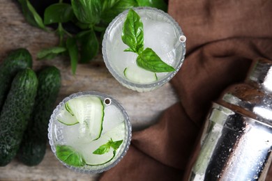 Photo of Glasses of refreshing cucumber water with basil on wooden table, flat lay