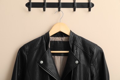 Hanger with black leather jacket on beige wall