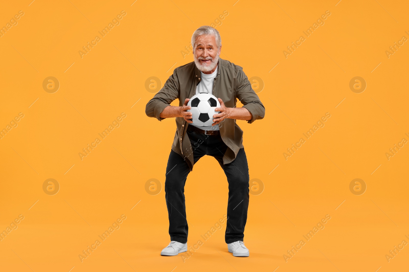 Photo of Happy senior sports fan with soccer ball on yellow background