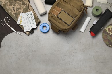 Photo of Flat lay composition with military first aid kit on light grey table. Space for text