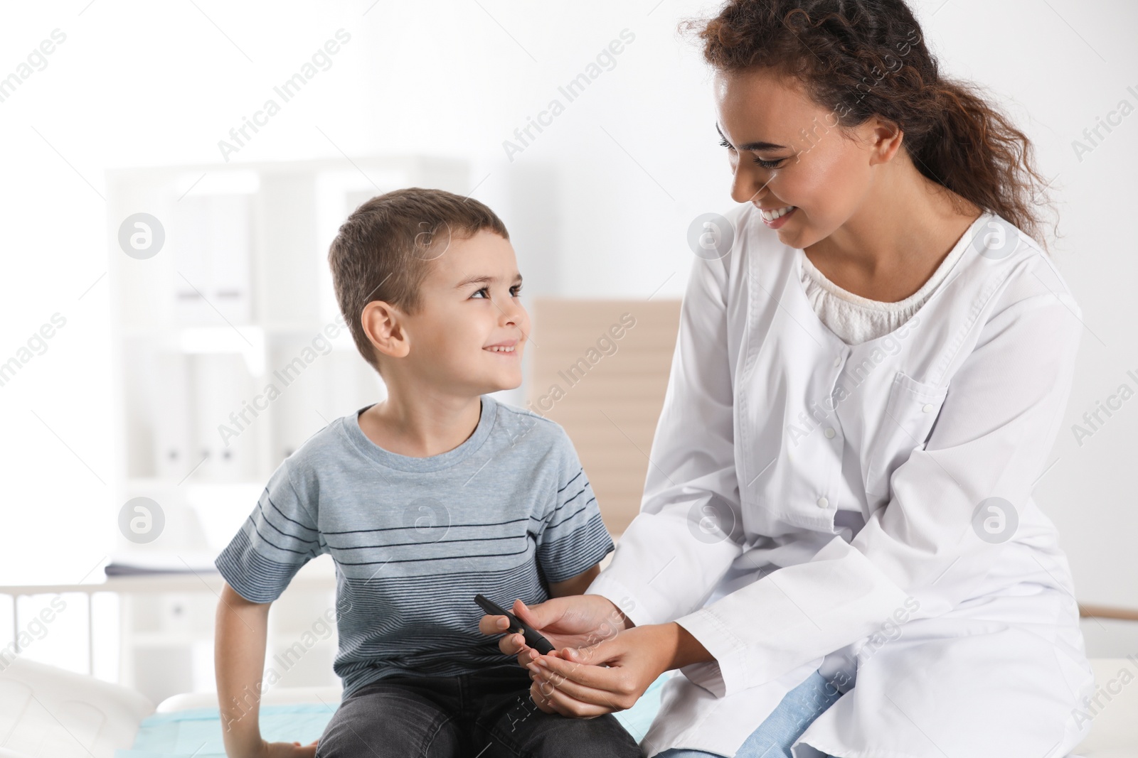 Photo of Doctor taking patient's blood sample with lancet pen in hospital. Diabetes control