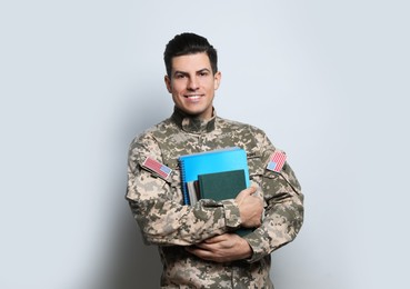 Photo of Cadet with books on grey background. Military education