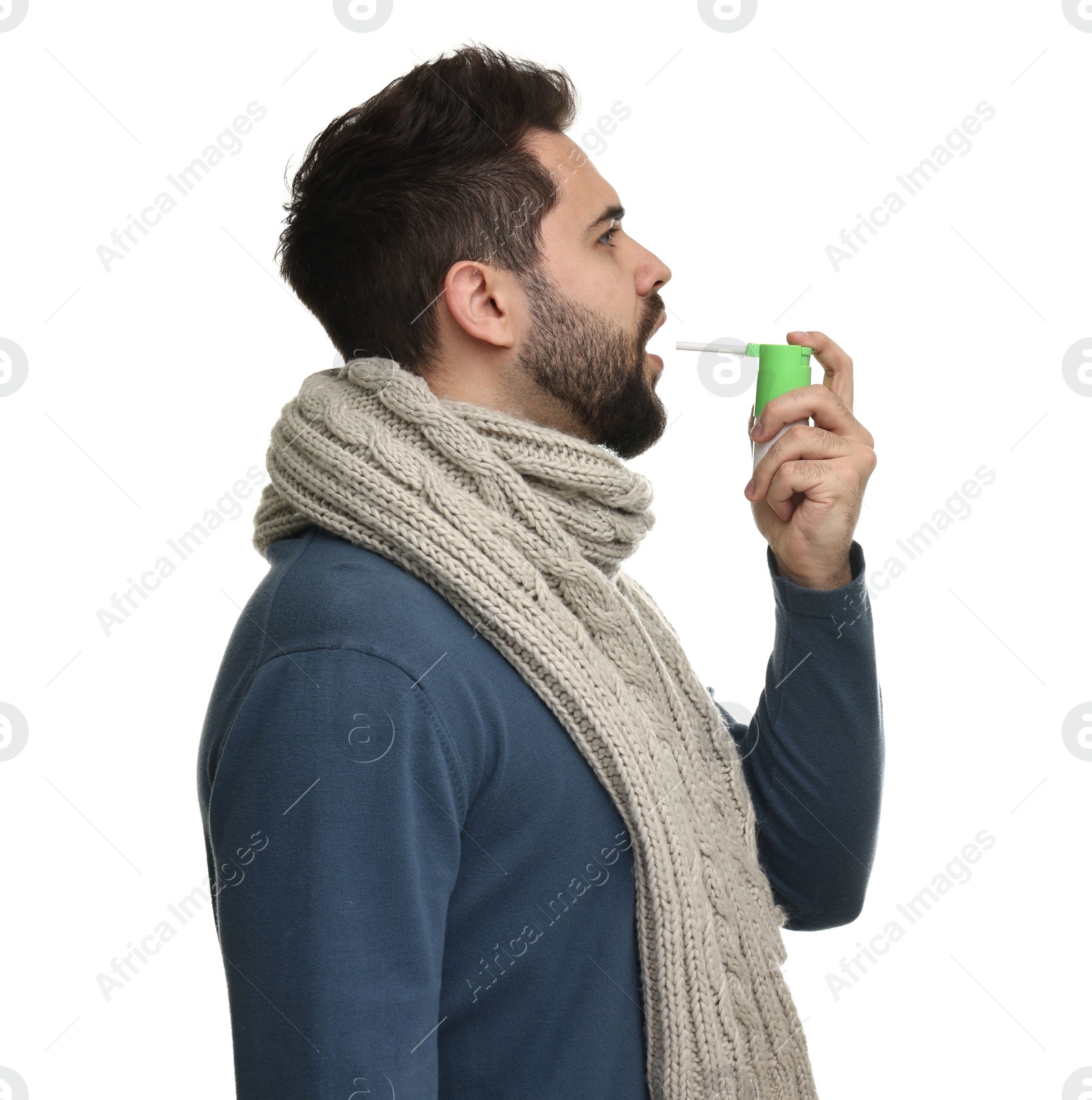 Photo of Young man with scarf using throat spray on white background