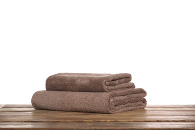 Soft brown terry towels on wooden table against white background