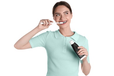 Photo of Young woman brushing teeth with charcoal toothpaste on white background