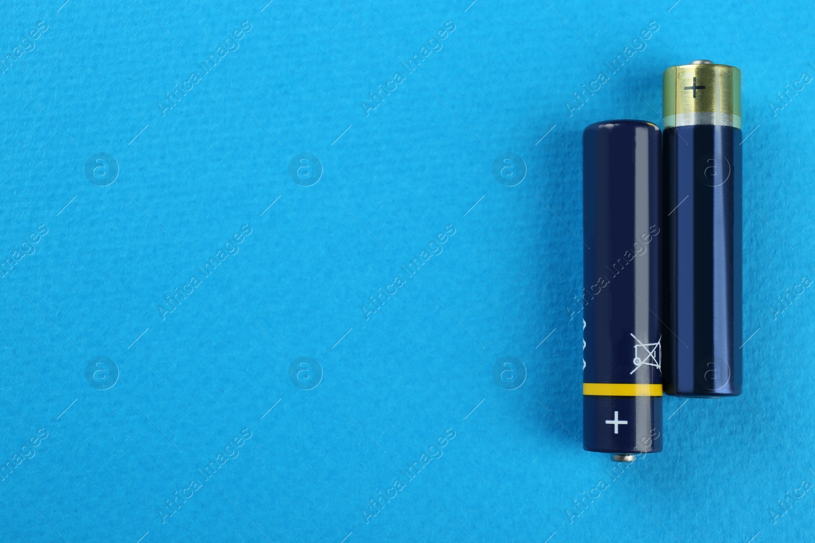 Image of New AAA batteries on turquoise background, flat lay. Space for text