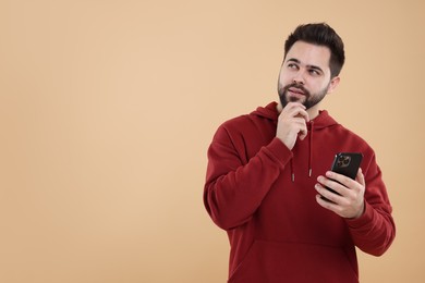Photo of Young man using smartphone on beige background, space for text