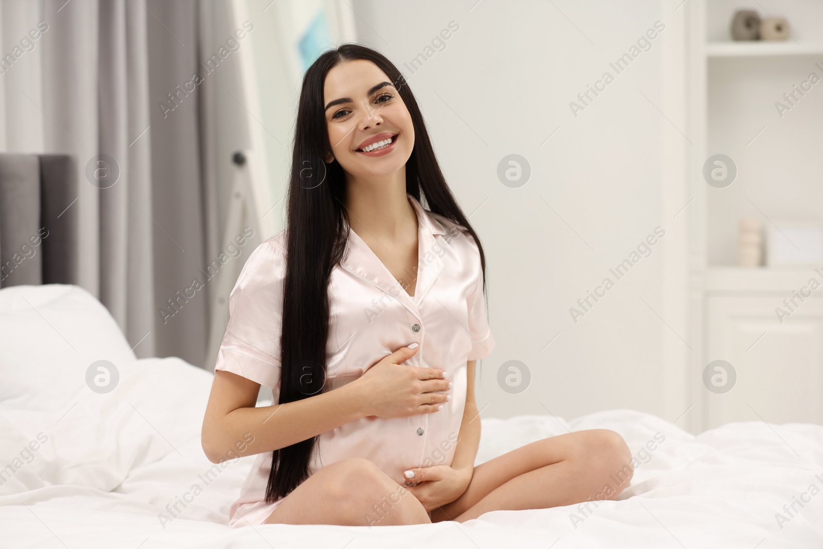 Photo of Happy pregnant woman on bed at home, space for text