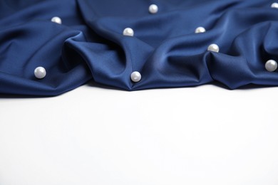 Photo of Texture of delicate dark blue silk with pearls on white background