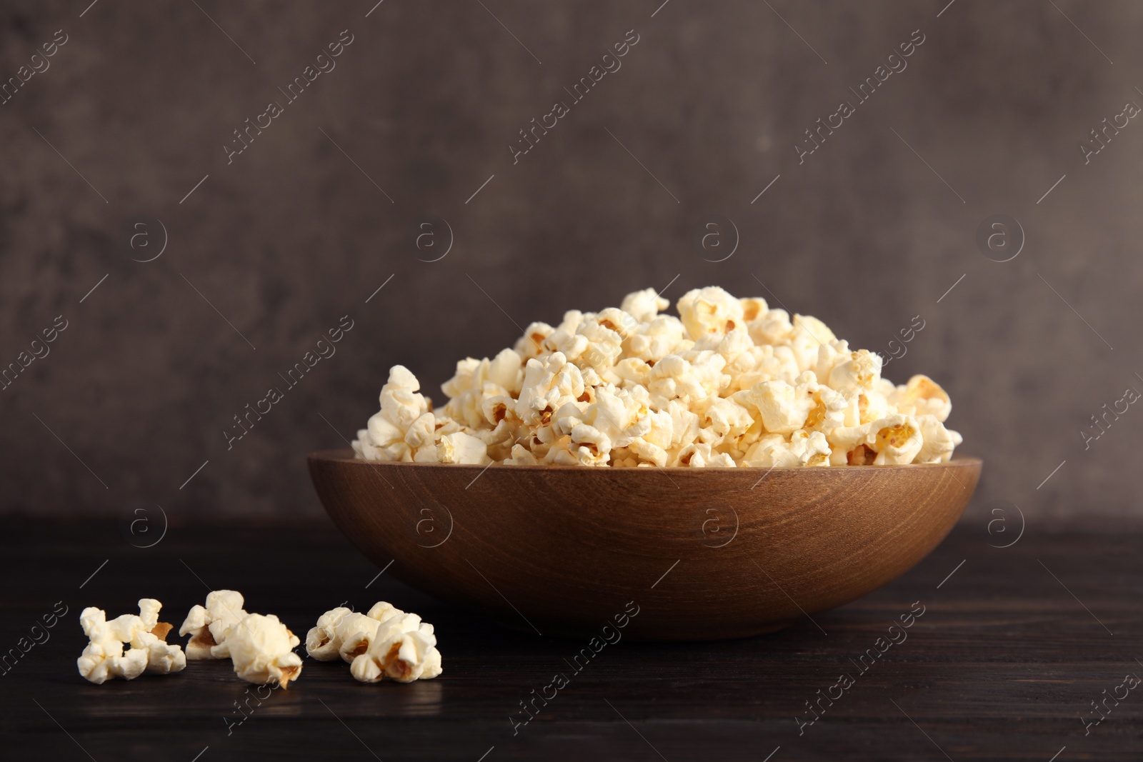 Photo of Bowl of tasty popcorn on wooden table
