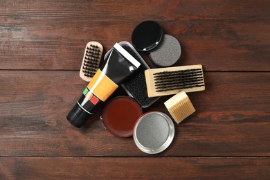 Flat lay composition with shoe care accessories on wooden background