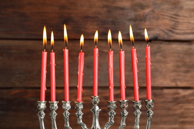 Photo of Silver menorah with burning candles on wooden background. Hanukkah celebration
