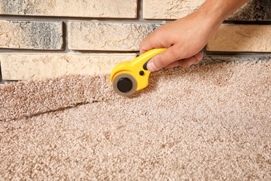 Man cutting new carpet flooring indoors, closeup