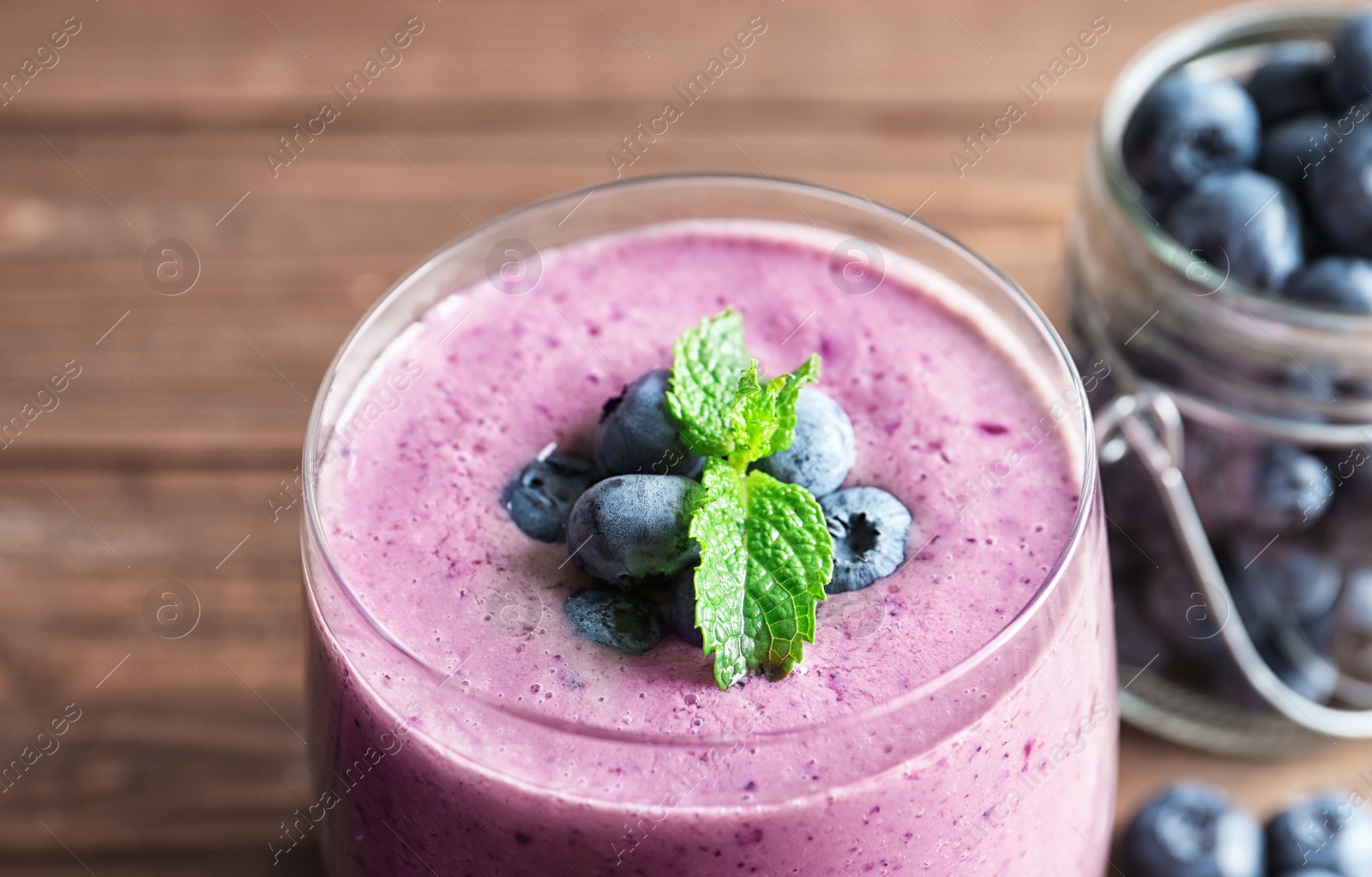 Photo of Blueberry smoothie with mint on table, closeup