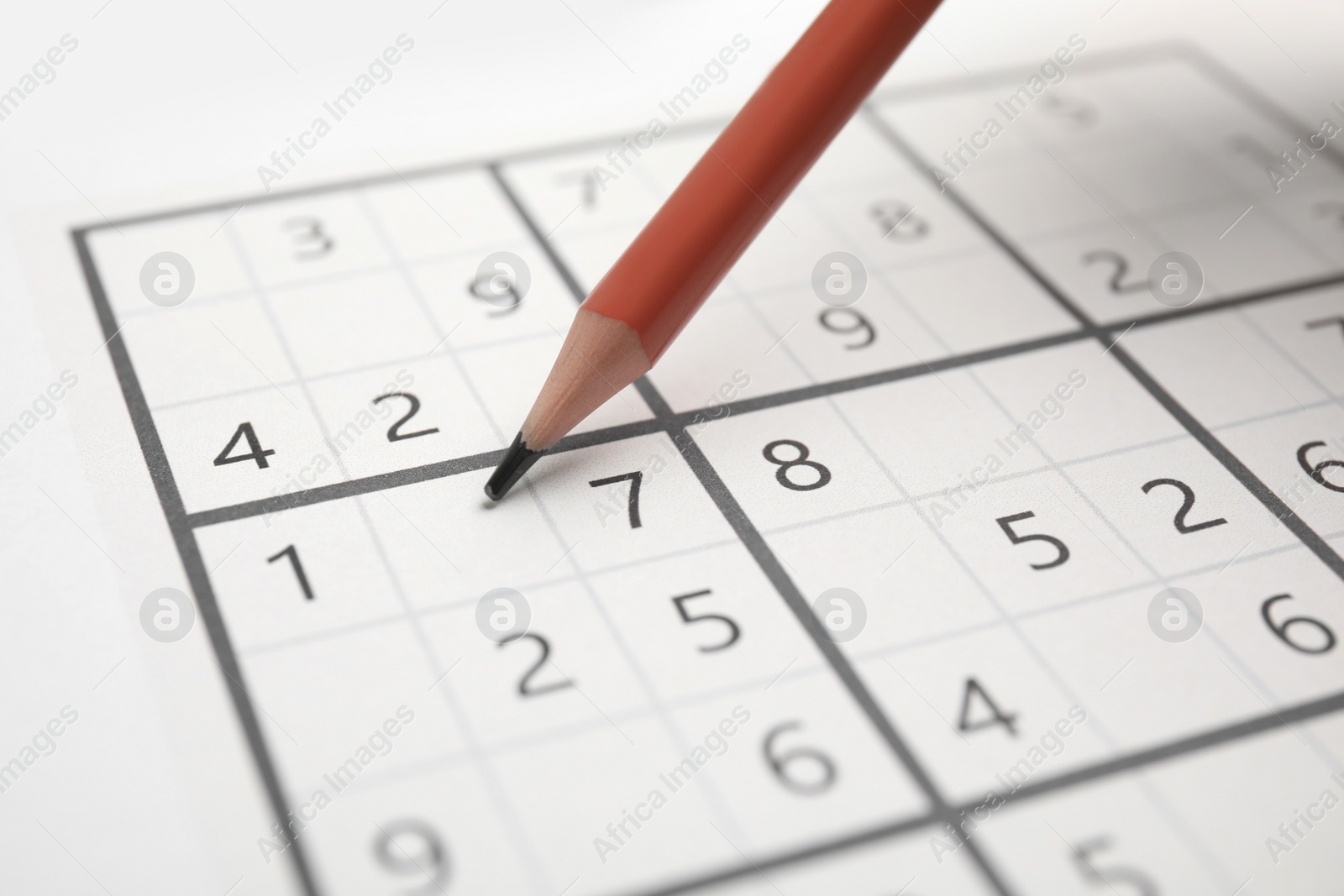 Photo of Sudoku puzzle grid and pencil, closeup view