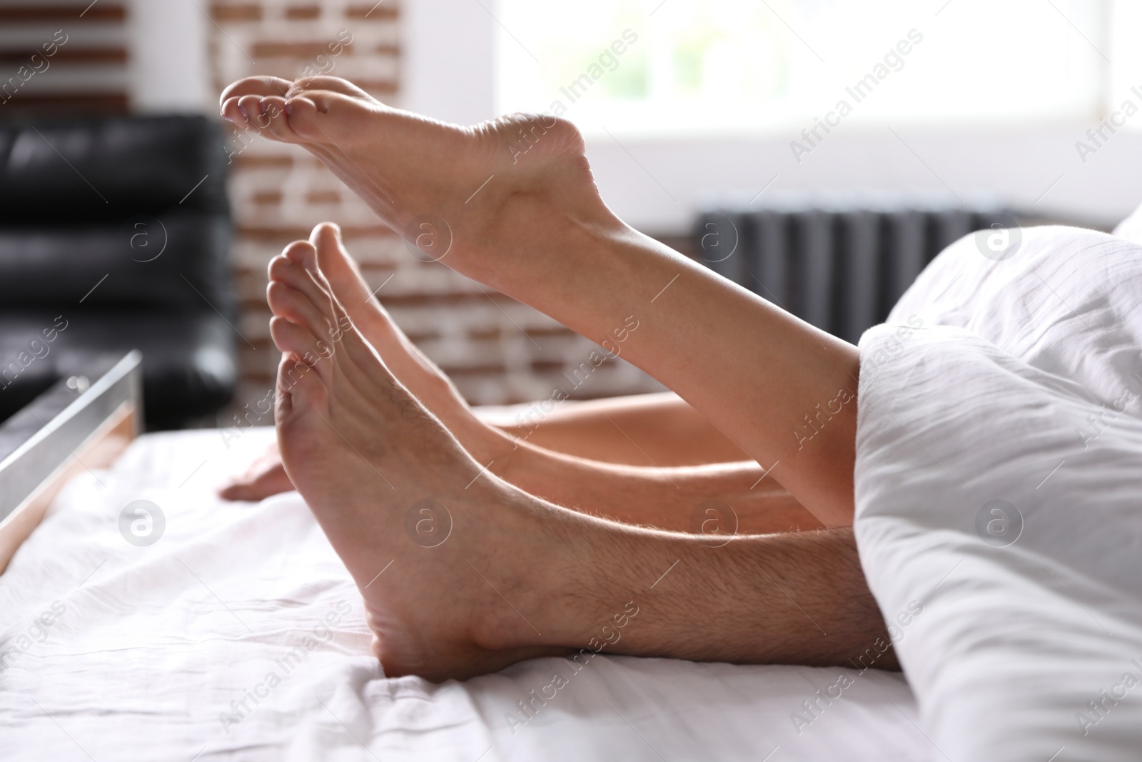 Photo of Passionate young couple having sex on bed at home, closeup of legs