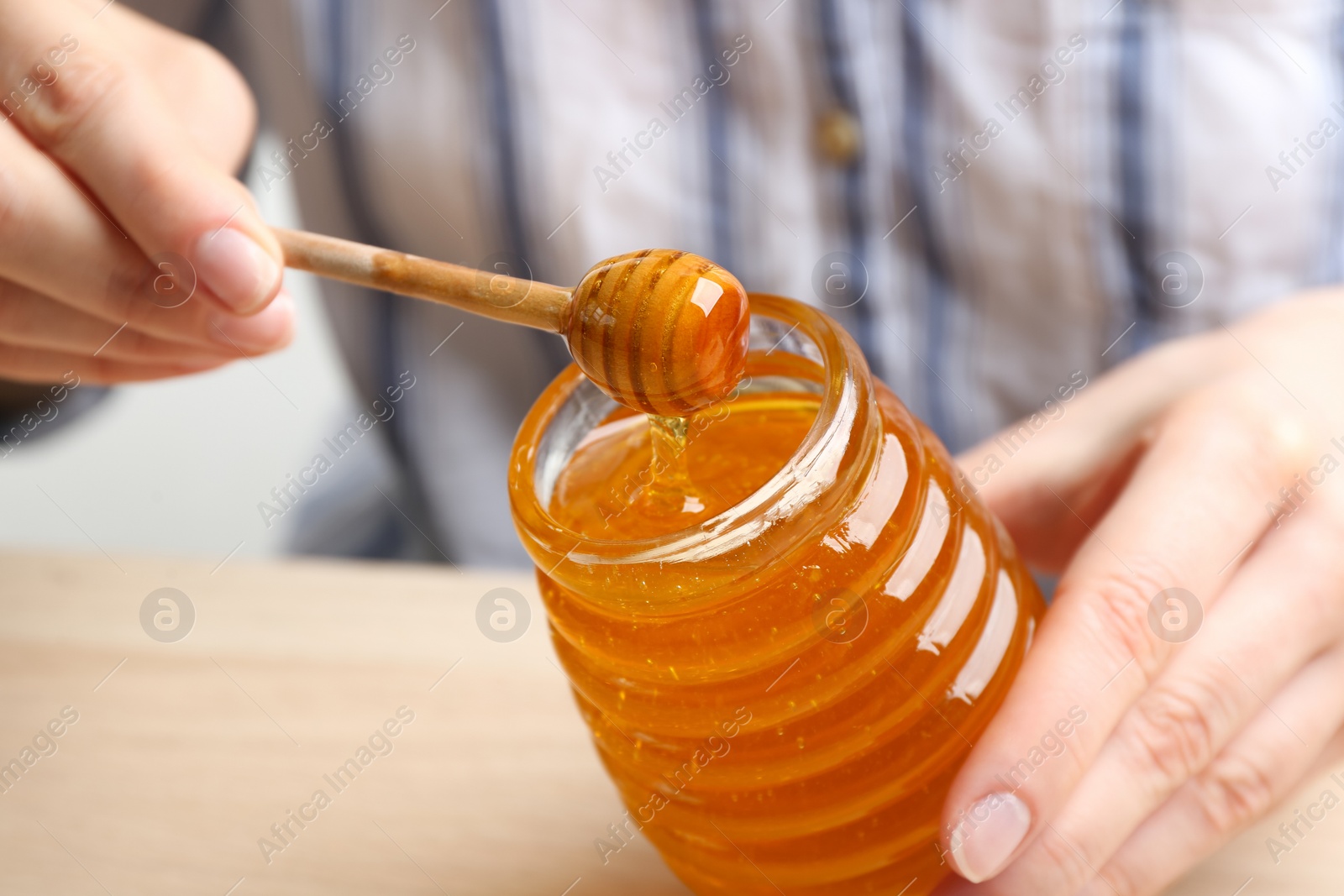 Photo of Woman with jar of honey at wooden table, closeup