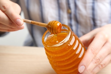 Photo of Woman with jar of honey at wooden table, closeup