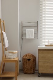 Photo of Heated rail with towel on white wall in bathroom